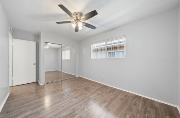 A room with a ceiling fan and wooden flooring.